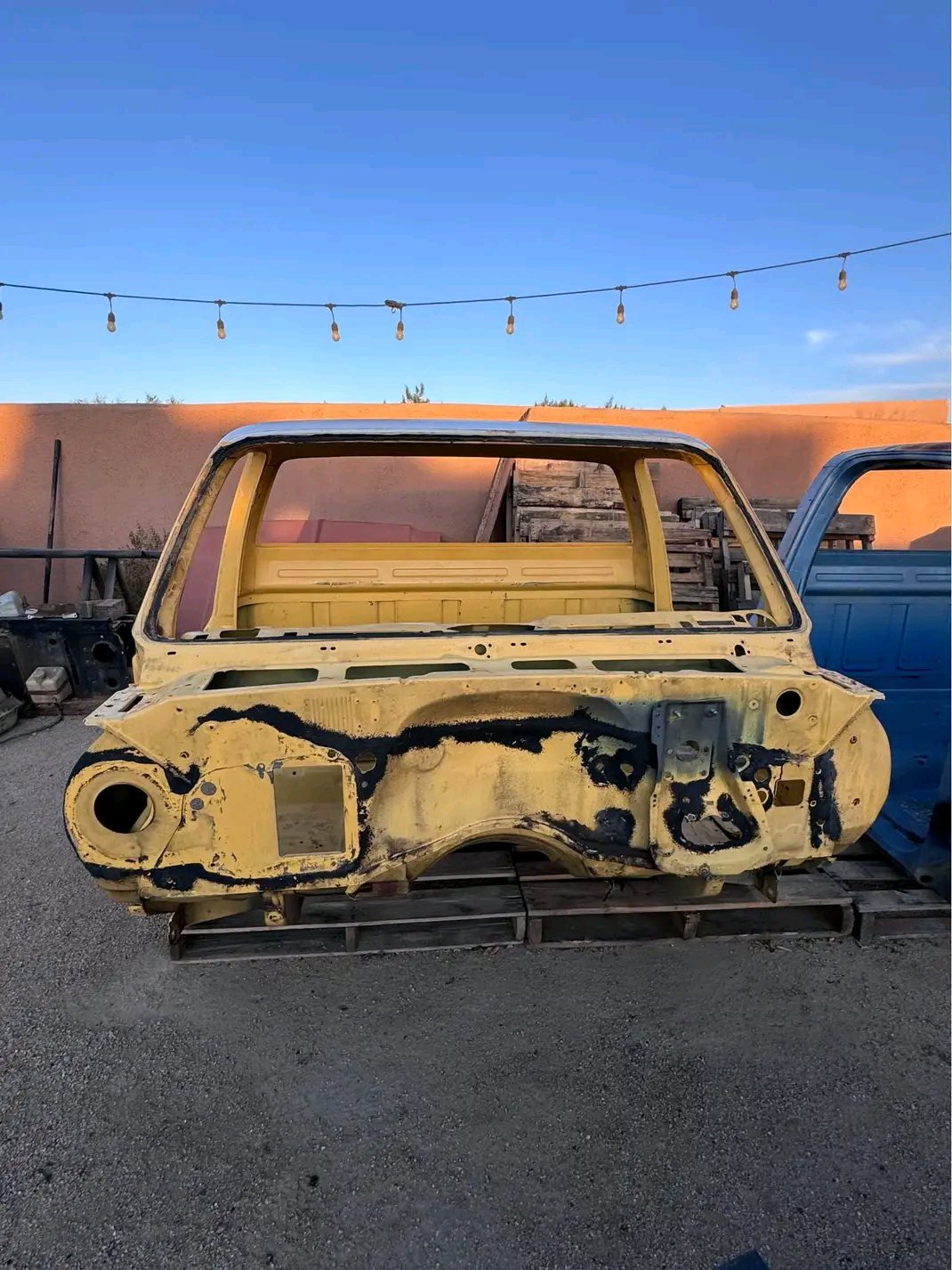 stripped metal cab from a classic 1973–1987 Chevrolet or GMC “square body” pickup truck, painted yellow with a white roof section. 
no doors